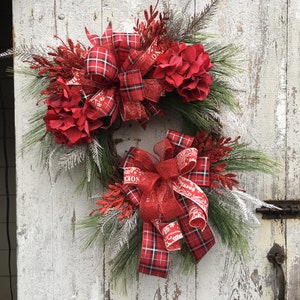 May include: A red and black plaid Christmas wreath with red poinsettia flowers and a red and white ribbon with a "Noel" print.