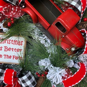 May include: A Christmas wreath with a red truck, red and black buffalo check ribbon, and a sign that reads "Christmas Is Better On The Farm".