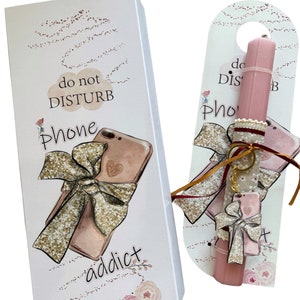 K&ouml;nnte beinhalten: Eine wei&szlig;e Schachtel und ein rosa T&uuml;rh&auml;nger mit einem Telefon-Thema. Die Schachtel hat eine Zeichnung eines Telefons mit einer goldenen Schleife und den Worten "do not DISTURB Phone addict". Der T&uuml;rh&auml;nger hat einen rosa lippenstiftf&ouml;rmigen Gegenstand mit einem Telefonanh&auml;nger.