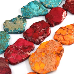 May include: A collection of irregular, flat, slab-shaped beads in a variety of vibrant colors including turquoise, deep red, bright pink, and orange. Each bead features a distinct, natural-looking veined pattern across its polished surface.