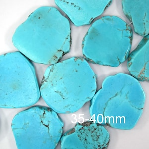 Può includere: Una collezione di lastre di pietra preziosa turchese piatte e irregolari con vivaci tonalità blu e venature a matrice marrone scuro. Le pietre sono disposte a grappolo e il testo 35-40mm è chiaramente visibile sulla superficie delle pietre.