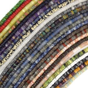 May include: Close-up of various strands of square-cut gemstone beads in a variety of colors. The beads are arranged diagonally, showcasing a spectrum of hues including green, red, yellow, black, white, and blue. The beads appear to be approximately 0.15 inches in size.