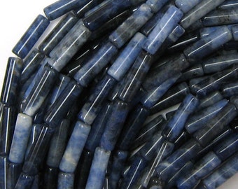 May include: A strand of blue and white gemstone beads, each bead is a long, thin cylinder. The beads are made of a natural stone with a marbled pattern.