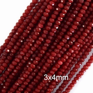 Puede incluir: Múltiples hileras de cuentas de cristal facetado de color rojo intenso dispuestas en filas paralelas. Cada cuenta tiene forma de rondel con la dimensión 3x4mm claramente impresa en texto blanco en la parte inferior de la imagen.