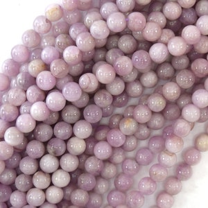 May include: A strand of round, light purple gemstone beads. The beads have a smooth, polished finish and a subtle shimmer.