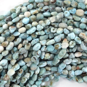 May include: A strand of light blue, white, and brown tumbled gemstone beads. The beads are irregularly shaped and have a natural, polished finish.