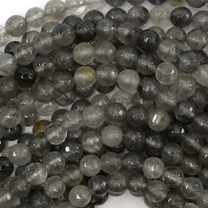 May include: A strand of round, faceted, smoky quartz beads. The beads are translucent and have a dark gray color.