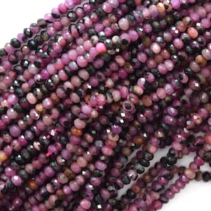 May include: A strand of faceted pink and black gemstone beads. The beads are small and round, and they have a shiny, polished finish.