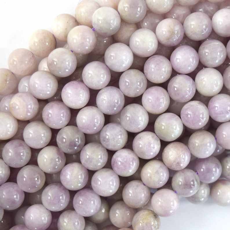 May include: A strand of round, pale lavender gemstone beads. The beads have a smooth, polished finish and a subtle shimmer.