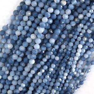 May include: A close-up view of a collection of faceted, round beads in varying shades of blue. The beads are strung together, creating a textured and visually appealing display. The beads are likely for jewelry making or crafting.