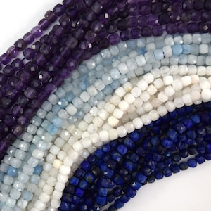 May include: A close-up of four strands of faceted gemstone beads. The top strand is amethyst, the second is aquamarine, the third is white moonstone, and the bottom strand is lapis lazuli.