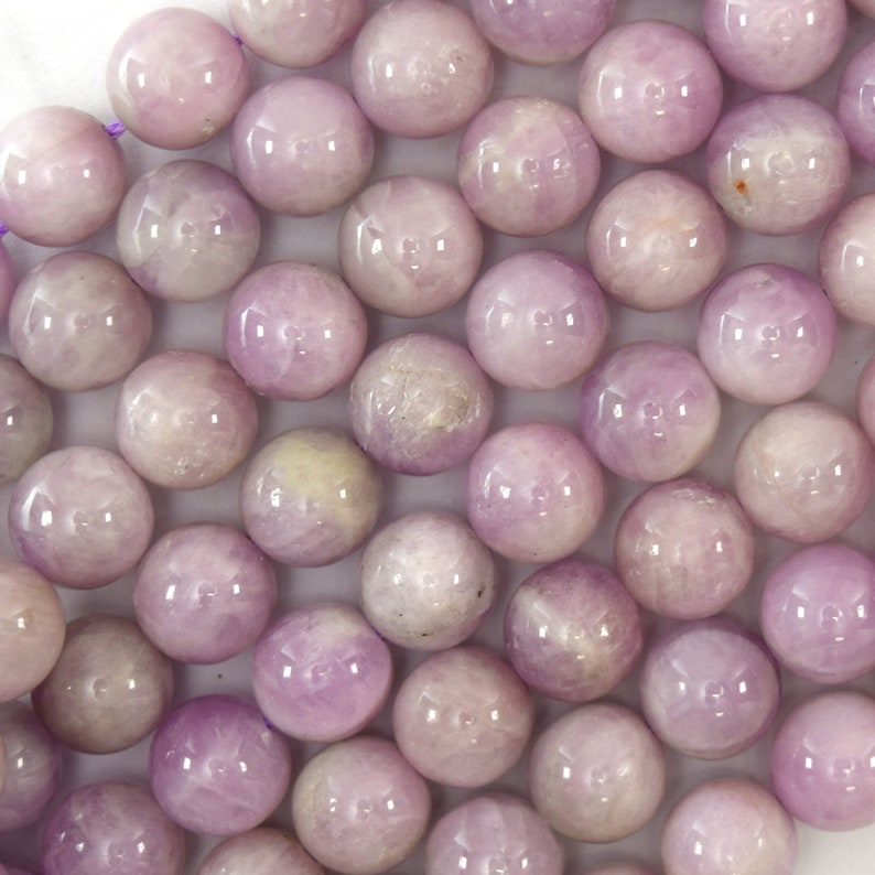 May include: A strand of round, light purple gemstone beads. The beads have a smooth, polished finish and a subtle shimmer.