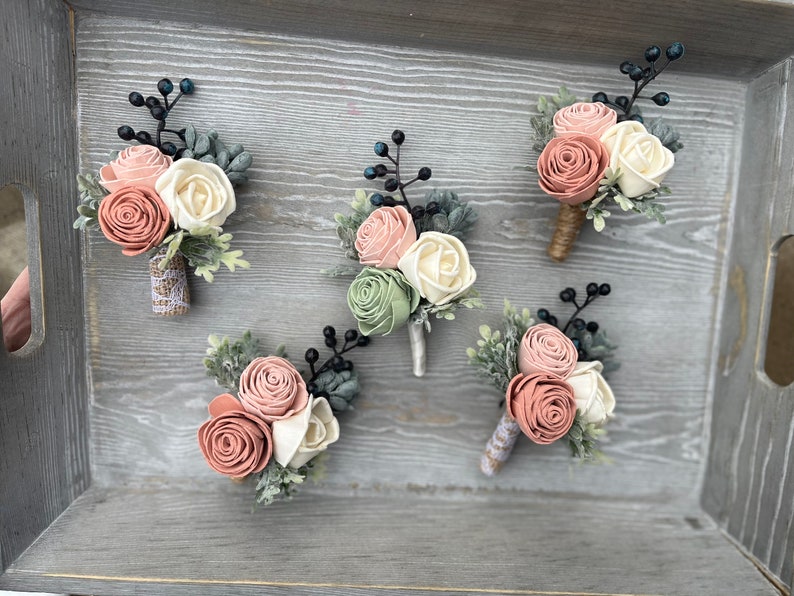 May include: Five small bouquets of artificial flowers in shades of pink, white, and green. Each bouquet is made with felt flowers and greenery, and is attached to a small piece of burlap.