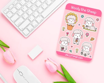 May include: A pink sticker sheet featuring cartoon sheep with floral accents and the text "Wooly the Sheep" and "JOLLITYPOP.COM". The sheet is surrounded by a white keyboard, mouse, eraser, pen, and pink tulips on a pink background.