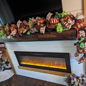 May include: A festive Christmas garland with red, green, and white bows and ribbons, decorated with candy canes and other holiday accents. The garland is draped over a wooden mantel above a fireplace.