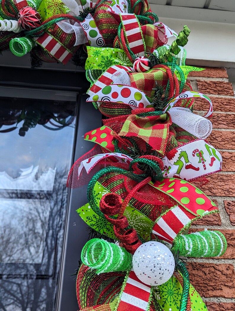 May include: A Christmas wreath with red, green, and white ribbon, mesh, and ornaments. The wreath is decorated with a variety of patterns, including polka dots, stripes, and snowflakes.