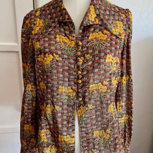 May include: A brown and yellow floral patterned blouse with a button-up front and long sleeves.