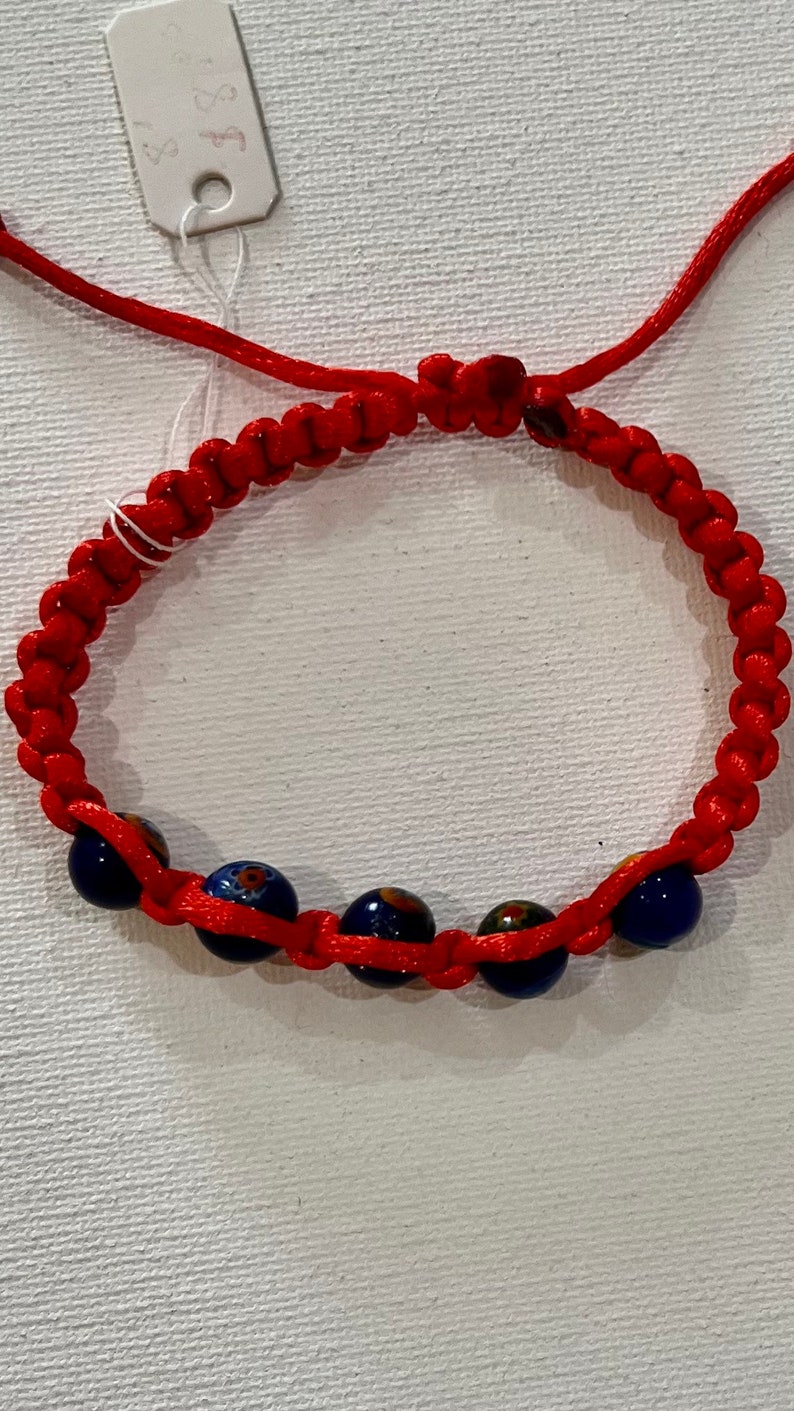 May include: Red string bracelet with blue and gold beads. The price tag says "$3.50".