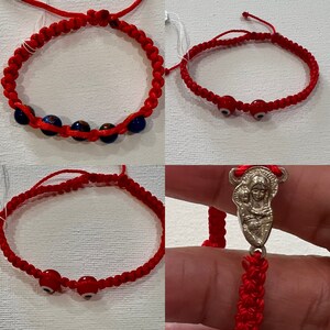 May include: Three red string bracelets with different charms. The first bracelet has blue and white glass beads. The second bracelet has two red evil eye beads. The third bracelet has a silver charm of the Virgin Mary and baby Jesus.