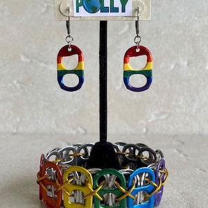 May include: Rainbow colored pull tab earrings and a bracelet made from pull tabs. The earrings are hanging from a display card that says "Planet Polly".