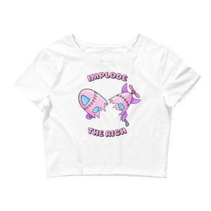May include: White cropped t-shirt with a pink and purple cartoon rocket design. The rocket is broken in half and the text "Implode the Rich" is printed below it.