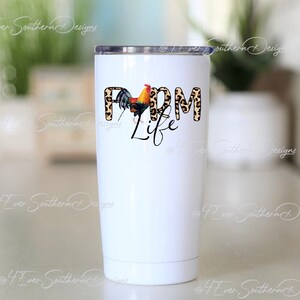 May include: A white stainless steel tumbler with a black lid. The tumbler features the words "Farm Life" in a mix of leopard print and black script, with a colorful rooster graphic.