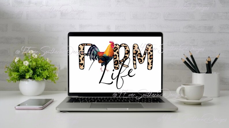 May include: A laptop displays the words "FARM LIFE" with a rooster illustration. The letters "FARM" have a leopard print design. The rooster is in shades of red, yellow, and black. The laptop is on a white desk with a coffee cup and a small plant.