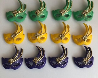 May include: Twelve Mardi Gras masks in three colors: green, yellow, and purple. Each mask has gold glitter and a gold design.