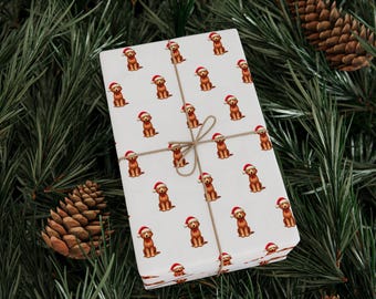 May include: A wrapped gift with a white background featuring a repeating pattern of brown dogs wearing Santa hats. The gift is tied with twine and rests on a bed of green pine needles and pine cones, creating a festive holiday scene.