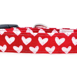 May include: Red dog collar with a white heart pattern.