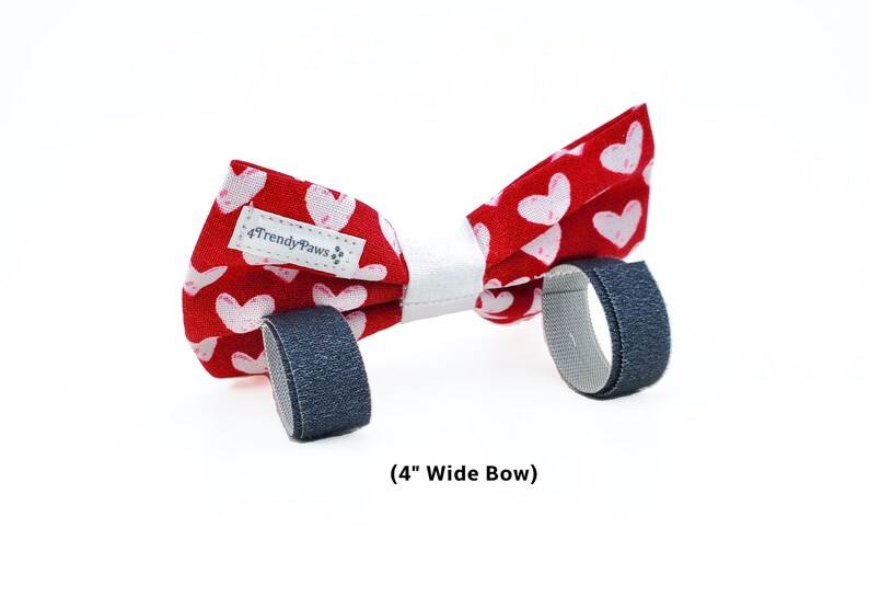 May include: Red bow tie with white hearts and a white centre, featuring adjustable velcro straps. The bow tie is 4 inches wide and has a "4TrendyPaws" label.