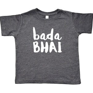 May include: A dark gray t-shirt with the words "bada BHAI" printed in white, a casual top for children. The shirt has short sleeves and a crew neck, suitable for everyday wear.