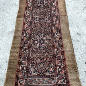 Puede incluir: Una alfombra larga y estrecha con un dise&ntilde;o persa tradicional. La alfombra tiene un fondo marr&oacute;n con un patr&oacute;n rojo, azul y blanco. La alfombra est&aacute; flecos en todos los lados.