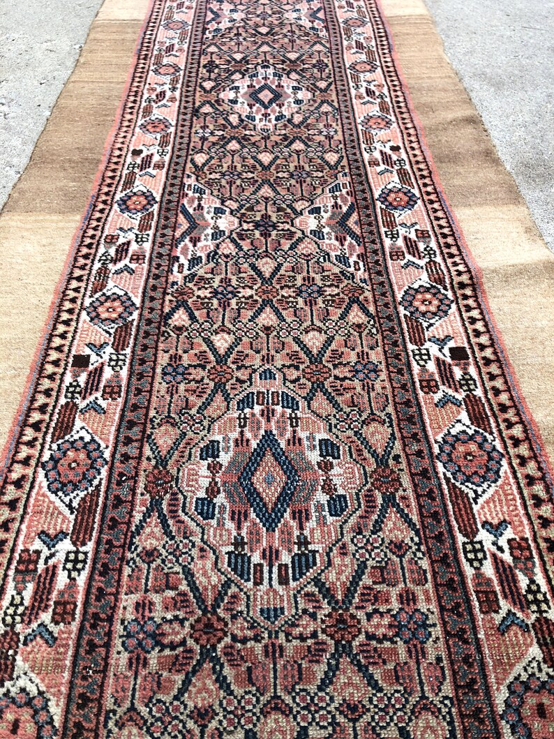 Puede incluir: Una alfombra larga y estrecha con un dise&ntilde;o persa tradicional. La alfombra es principalmente en tonos de rosa, rojo y azul, con intrincados patrones florales y geom&eacute;tricos. La alfombra tiene flecos en ambos extremos.