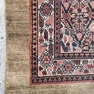 Puede incluir: Primer plano de una alfombra de color marr&oacute;n y rojo con un borde de flecos. La alfombra tiene un dise&ntilde;o floral con detalles intrincados.