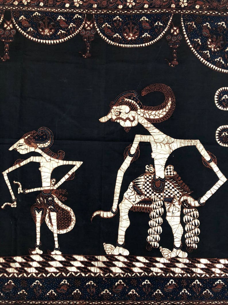 Op de afbeelding: Zwart-witte batikstof met een traditioneel Indonesisch ontwerp met twee figuren met ingewikkelde details. De figuren staan op een gepatroneerde achtergrond.