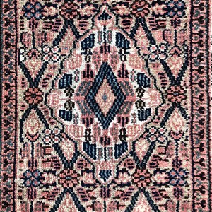 Puede incluir: Una alfombra vintage con un patr&oacute;n geom&eacute;trico rosa, azul y negro. La alfombra tiene una forma de diamante central con intrincados dise&ntilde;os florales.