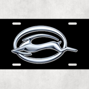 May include: A black license plate with a silver Chevrolet Impala logo featuring a stylized running deer in a circle.