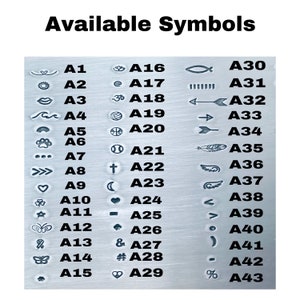May include: A chart of available symbols for customization. The symbols are organized in two columns with a letter and number code next to each symbol. The symbols include a heart, a sun, a wave, a paw print, a cross, a crescent moon, a star, a butterfly, a feather, an arrow, a fish, a peace sign, a music note, a number sign, and more.
