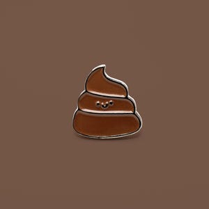 Op de afbeelding: Een bruine emaille pin in de vorm van een lachende poep emoji. De pin heeft een zilveren omtrek en een ontwerp met drie lagen. De achtergrond is effen bruin.
