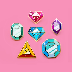 Pode incluir: Seis broches de esmalte em forma de diferentes gemas com rostos fofinhos. Os broches são de várias cores, incluindo rosa, azul, verde e roxo.