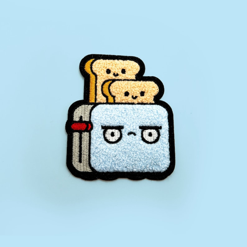 May include: A blue embroidered patch of a toaster with a grumpy expression and two slices of bread popping up. The toaster has a red lever and a black outline.