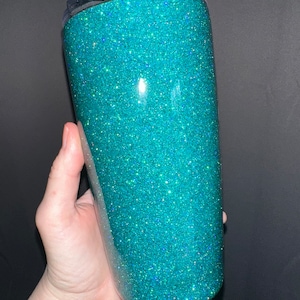 May include: A teal glitter tumbler with a clear lid. The tumbler is made of stainless steel and has a double-wall construction to keep drinks cold or hot for hours.