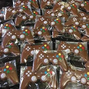 May include: A group of individually wrapped chocolate game controllers. Each controller is brown with colorful buttons and a gray center button. The text "Desserts For Days" is visible in the image.