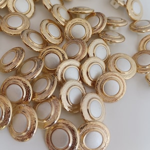 the photo shows gold tone metal and pearly white plastic buttons