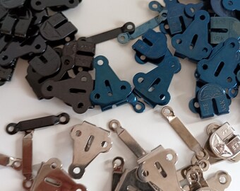 May include: Assortment of metal garment fasteners in black, blue, and silver. The fasteners are in the shape of a triangle with a small hole in the center. The fasteners are used to attach clothing together.