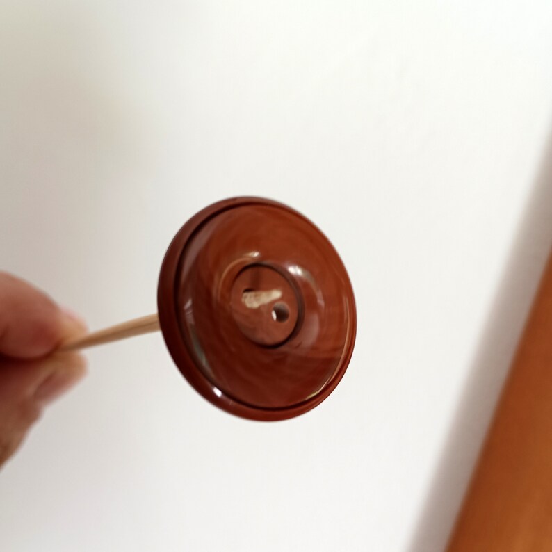A brown button attached to a wooden stick.