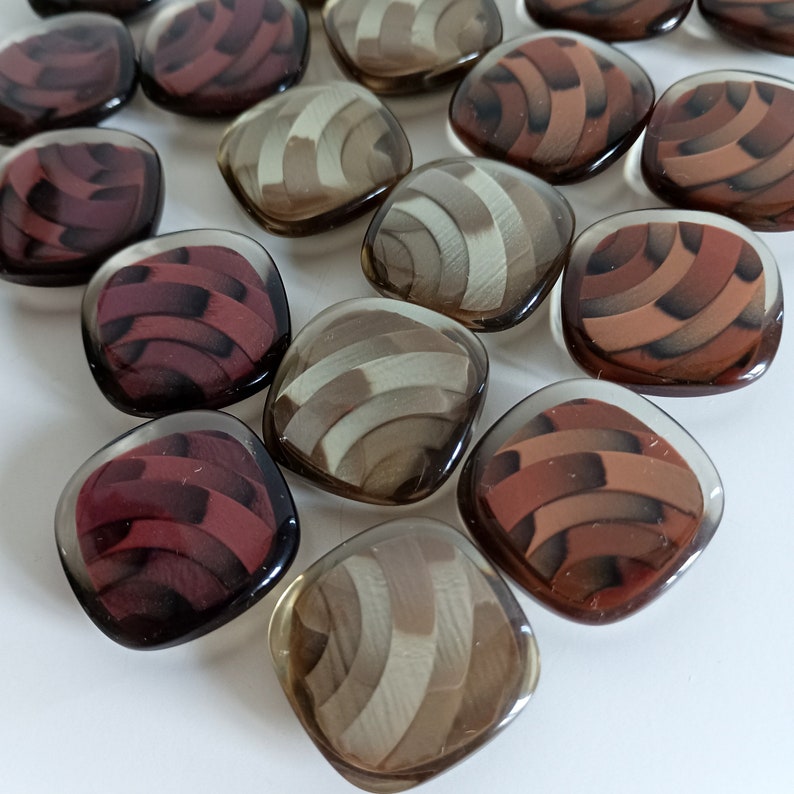 the photo shows clear plastic buttons square shaped in the three available colors: beige, burgundy, brown