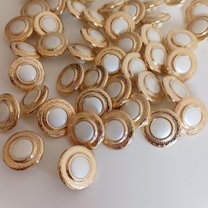 the photo shows gold tone metal and pearly white plastic buttons