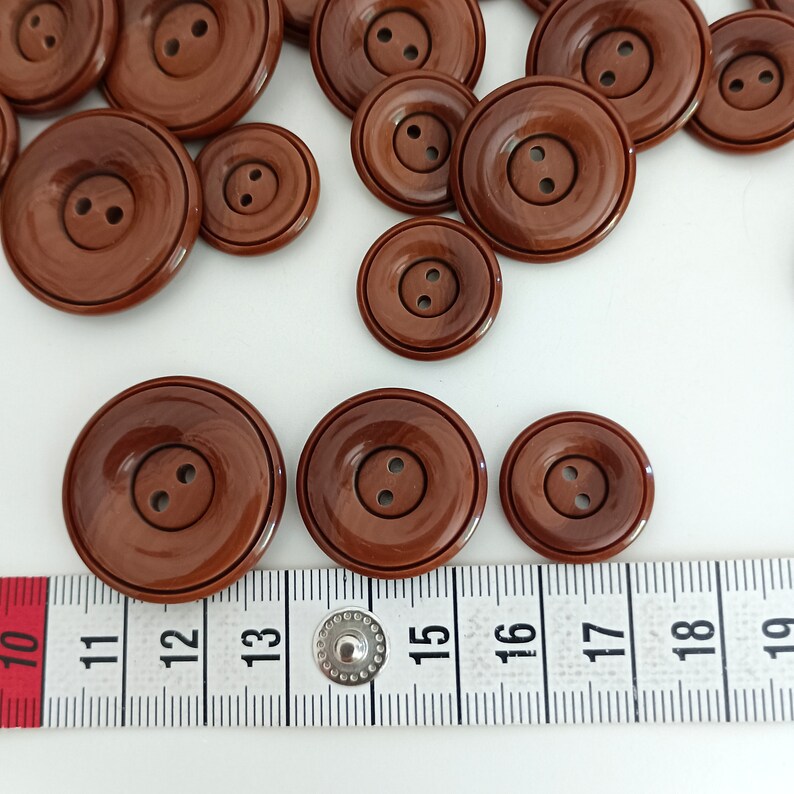the buttons are photographed next to a tape measure
button size: 28mm - 23mm - 18mm